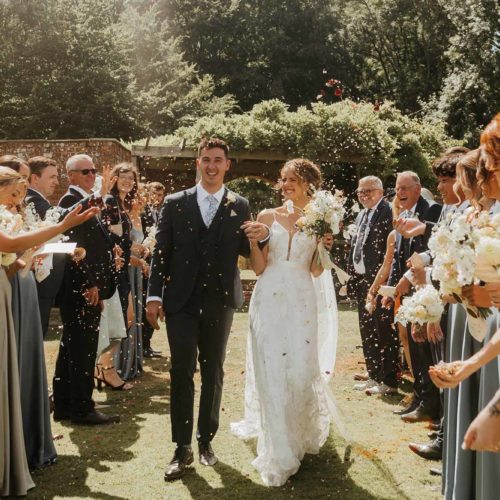 Bride-and-groom-showered-with-confetti-by-guests-on-Homme-House-long-borders