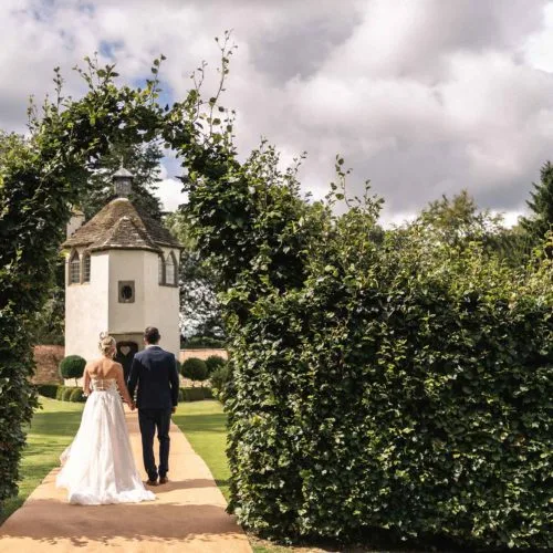 Bride-and-groom-walk-down-aisle-carpet-towards-Homme-House-Summerhouse