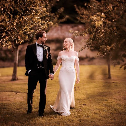 Bride-and-groom-walk-through-orchard-at-Homme-House