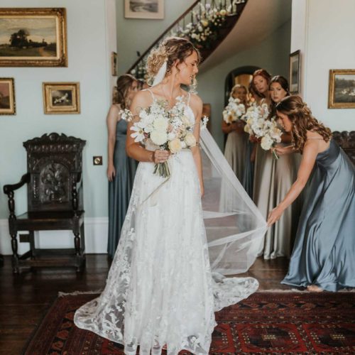 Bridesmaid-adjusts-bridal-veil-in-Hall-at-Homme-House