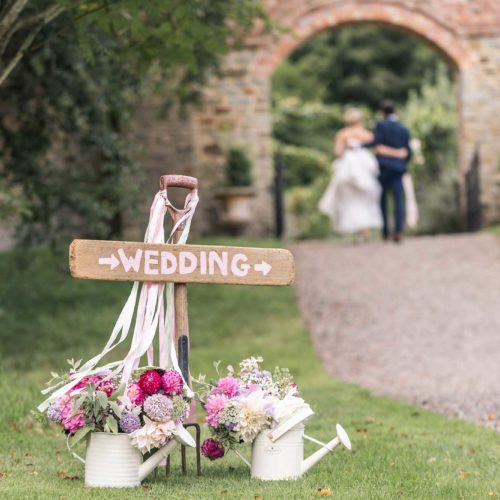 Garden-wedding-sign-with-couple-in-background