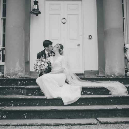 Portrait-of-bride-and-groom-kissing-on-the-steps-of-Homme-House