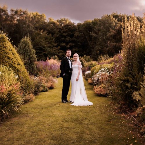 Portrait-of-bride-and-groom-on-long-borders-in-Homme-House-walled-garden