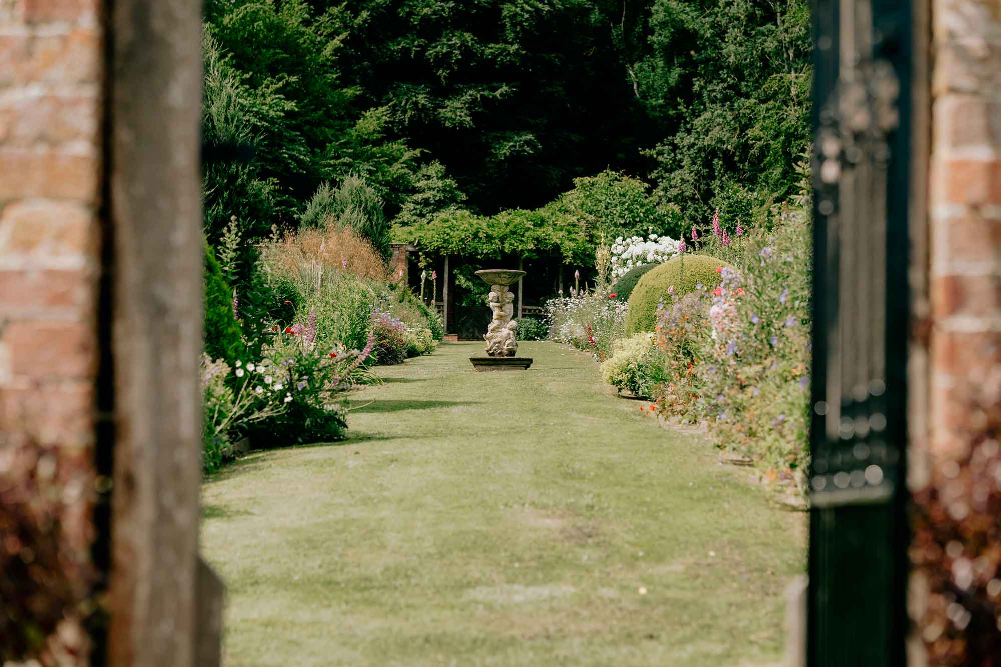 Homme-House-long-borders-viewed-through-walled-garden-gate